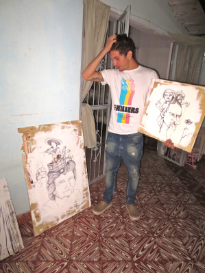 Sanabria with two of his paintings. (Photo used with permission from the VISPERA.) 